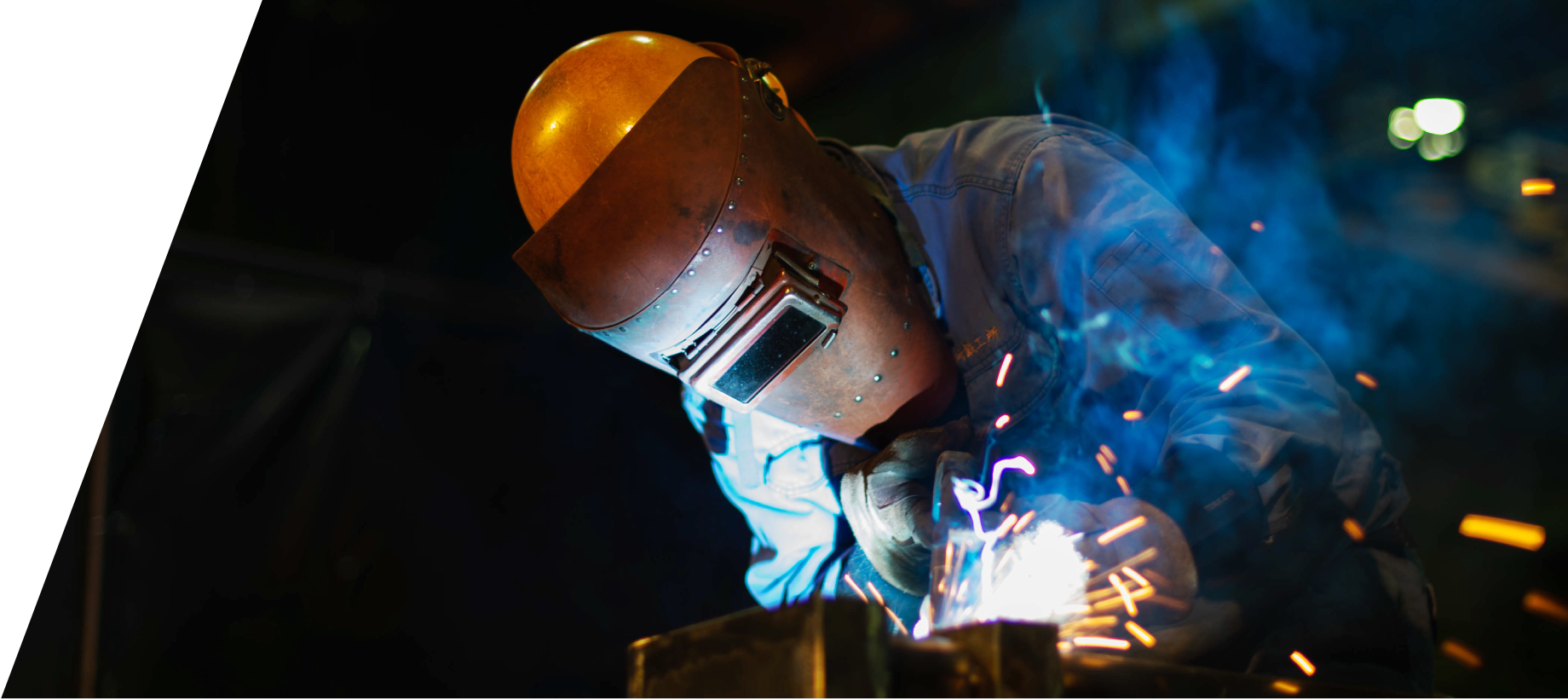 Employee welding using a handheld welding mask